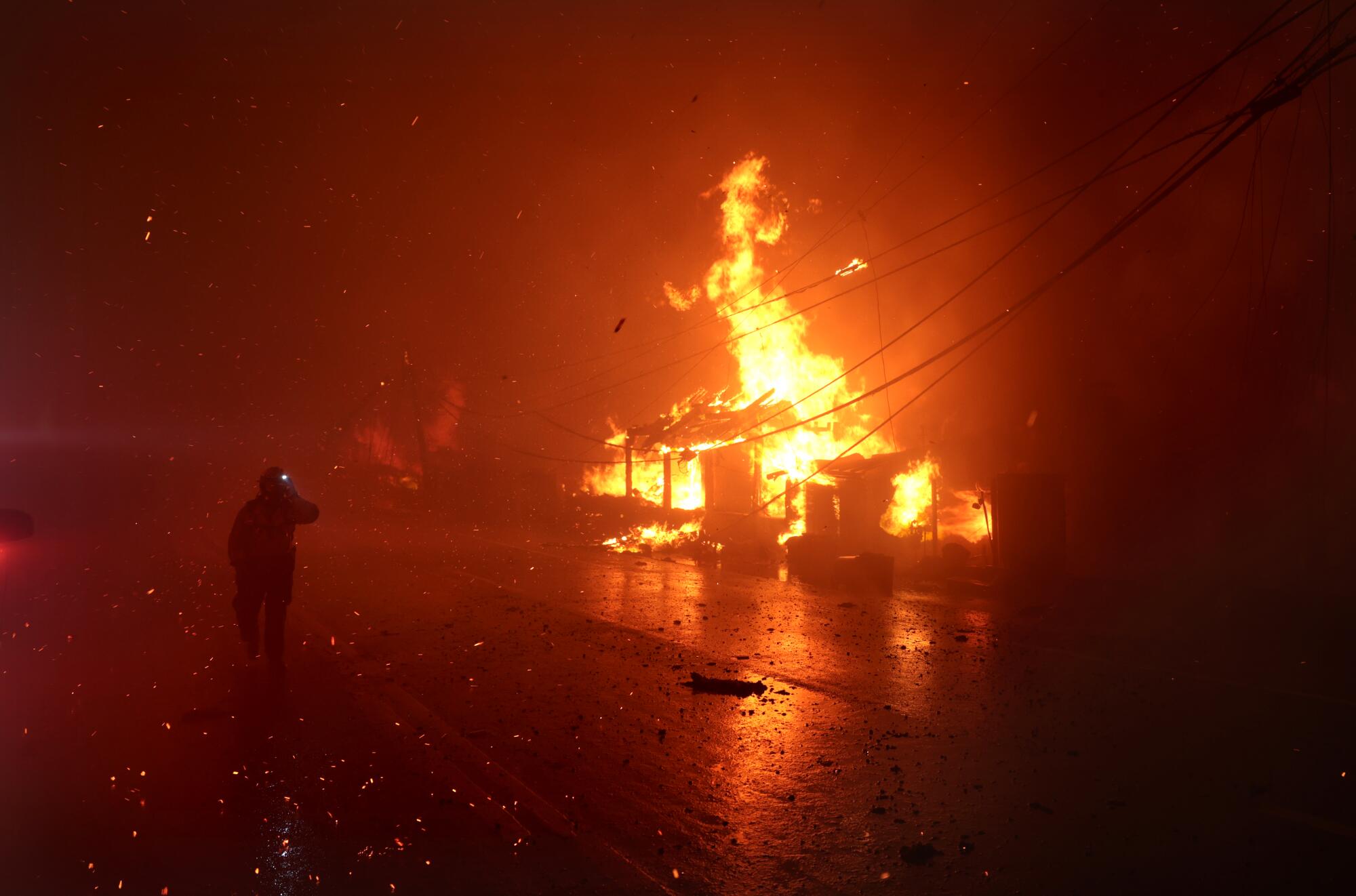 A firefighter battles the Palisades blaze as homes burn along Pacific Coast Highway in Malibu on Jan. 8.