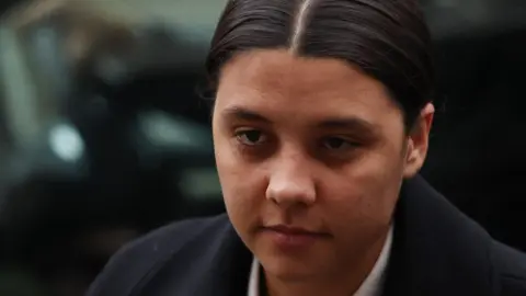 PA Media Sam Kerr arriving at court in a suit, looking serious