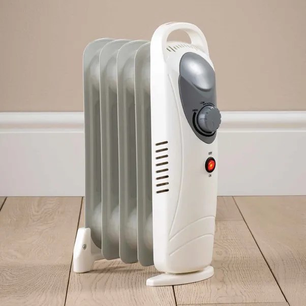 White electric oil-filled radiator heater on wood floor.