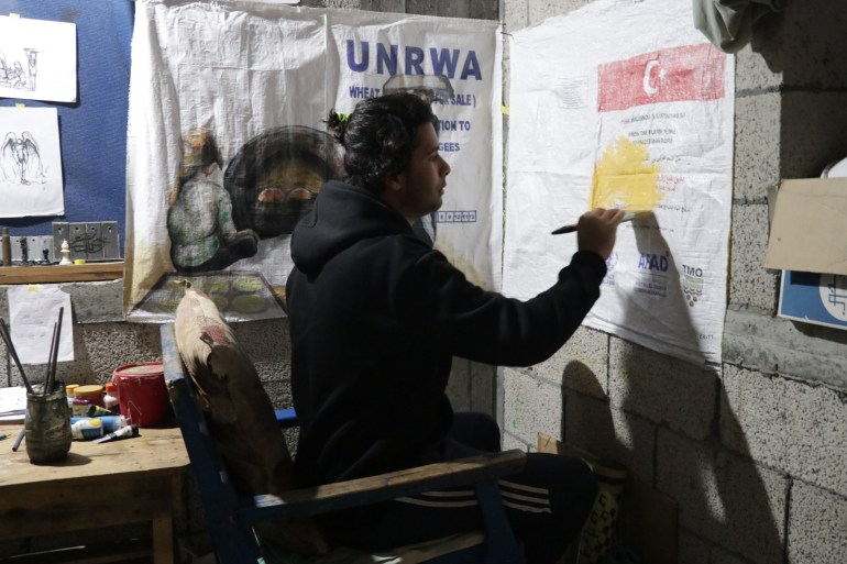 Artist Hussein Al Jerjawi works in his temporary studio, repurposing discarded UNRWA flour bags as canvases to document life under siege.