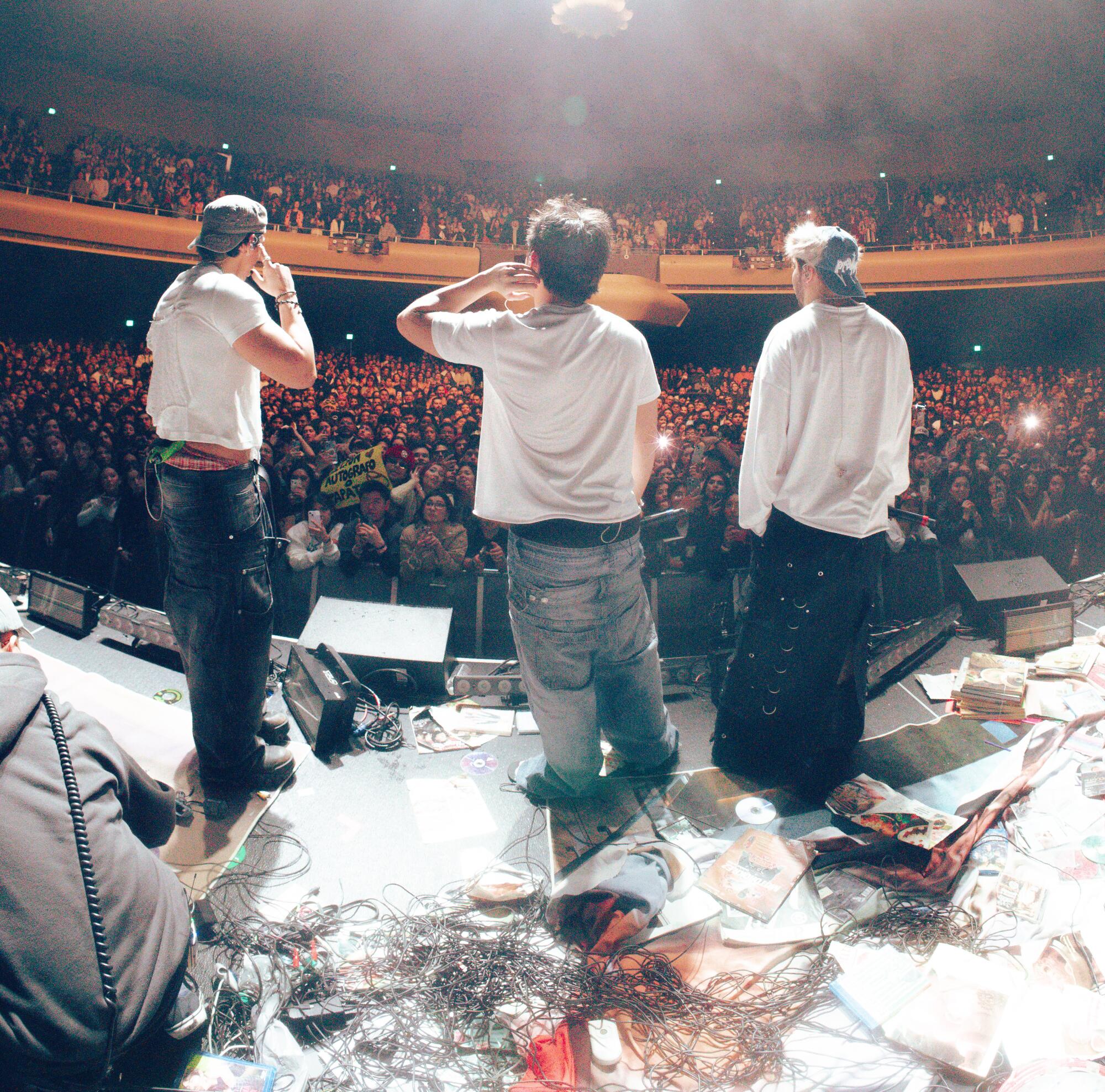 Three men perform on a stage.