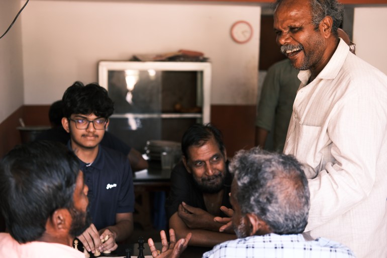 Charaliyil Unnikrishnan (middle) sits next to Gowrishankar Jayaraj, while Baby John (standing) laughs. Unnikrishnan, a former Maoist rebel, brought ches to the village [Mirja Vogel/Al Jazeera]