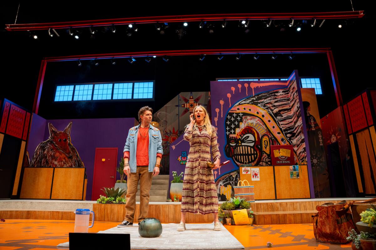 A man and a woman onstage, facing the audience, before a colorful backdrop