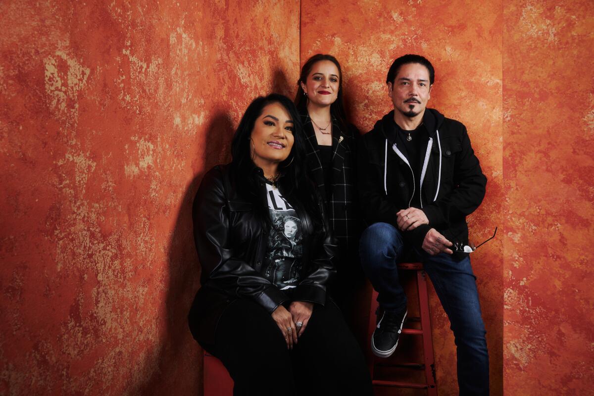 Two women and a man against an orange backdrop