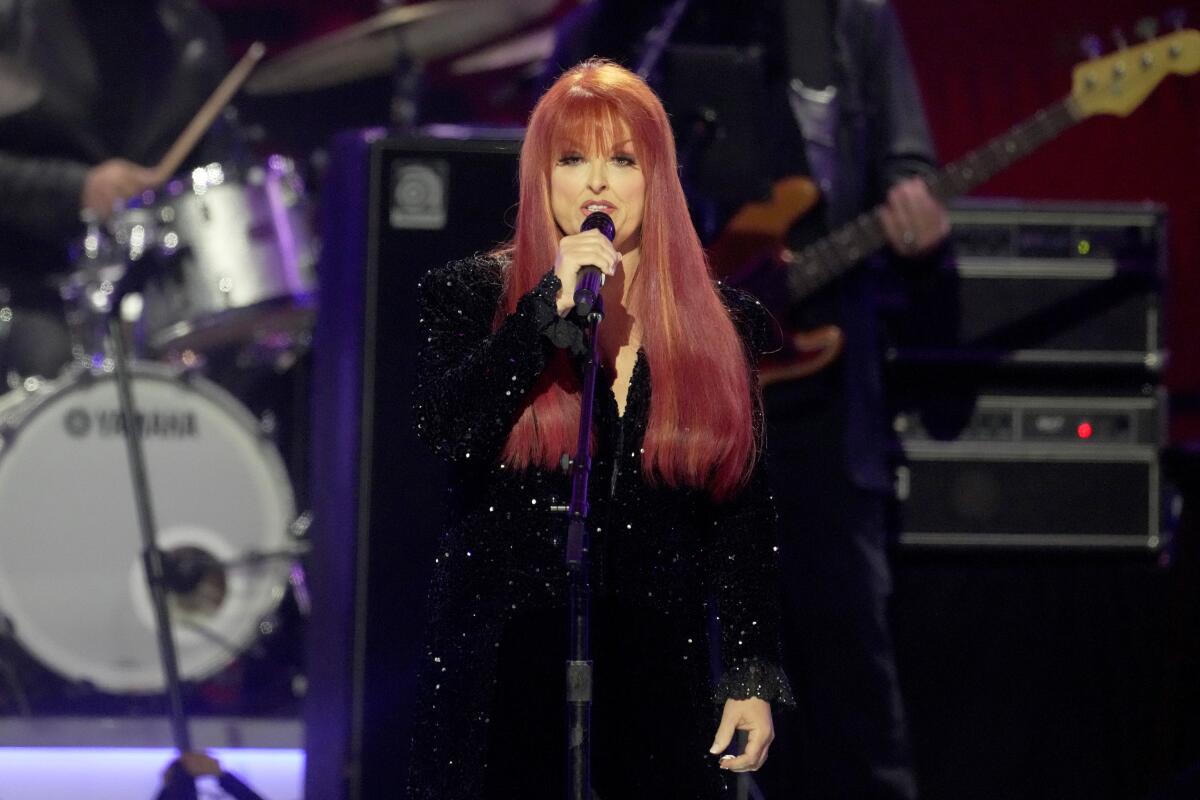 Wynonna Judd performs in a sparkly black outfit.