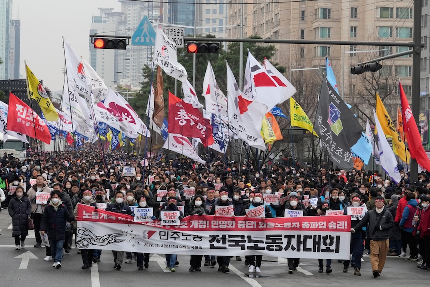 Thousands march with banners and flags on the streets of Seoul.