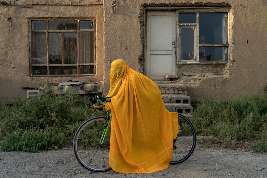 An Afghan woman poses for a photo on her bicycle wearing a burqa in Kabul.