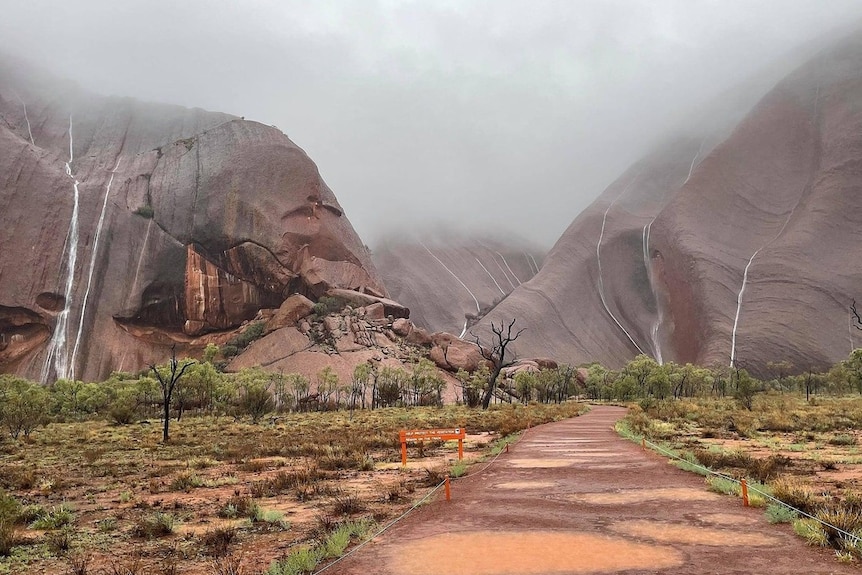 Waterfalls across Uluru covered in fog