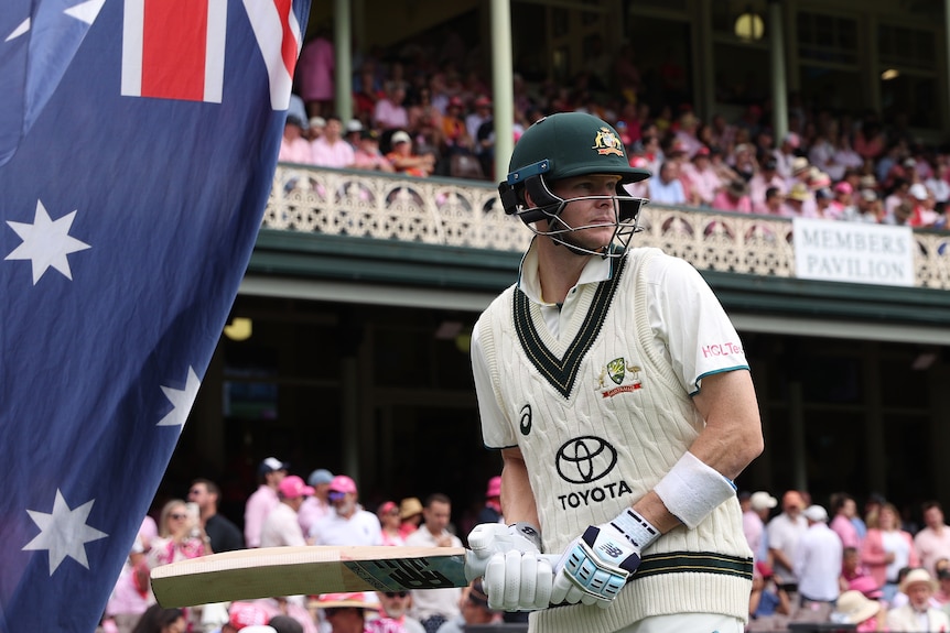 Steve Smith prepares to run onto the field next to an Australian flag