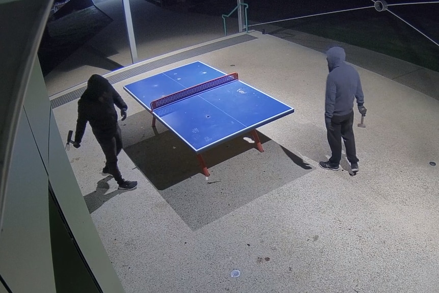 CCTV footage of two hooded men holding tools near a damaged table tennis table.