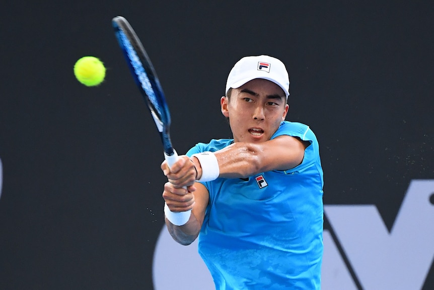 A man clenches his hands on to a tennis racquet while keeping his eye on a tennis ball.