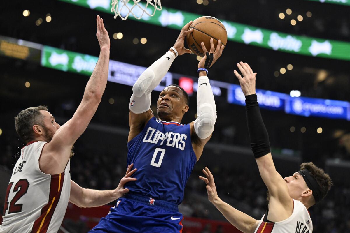 Clippers guard Russell Westbrook shoots between Miami Heat forward Kevin Love, left, and guard Tyler Herro.