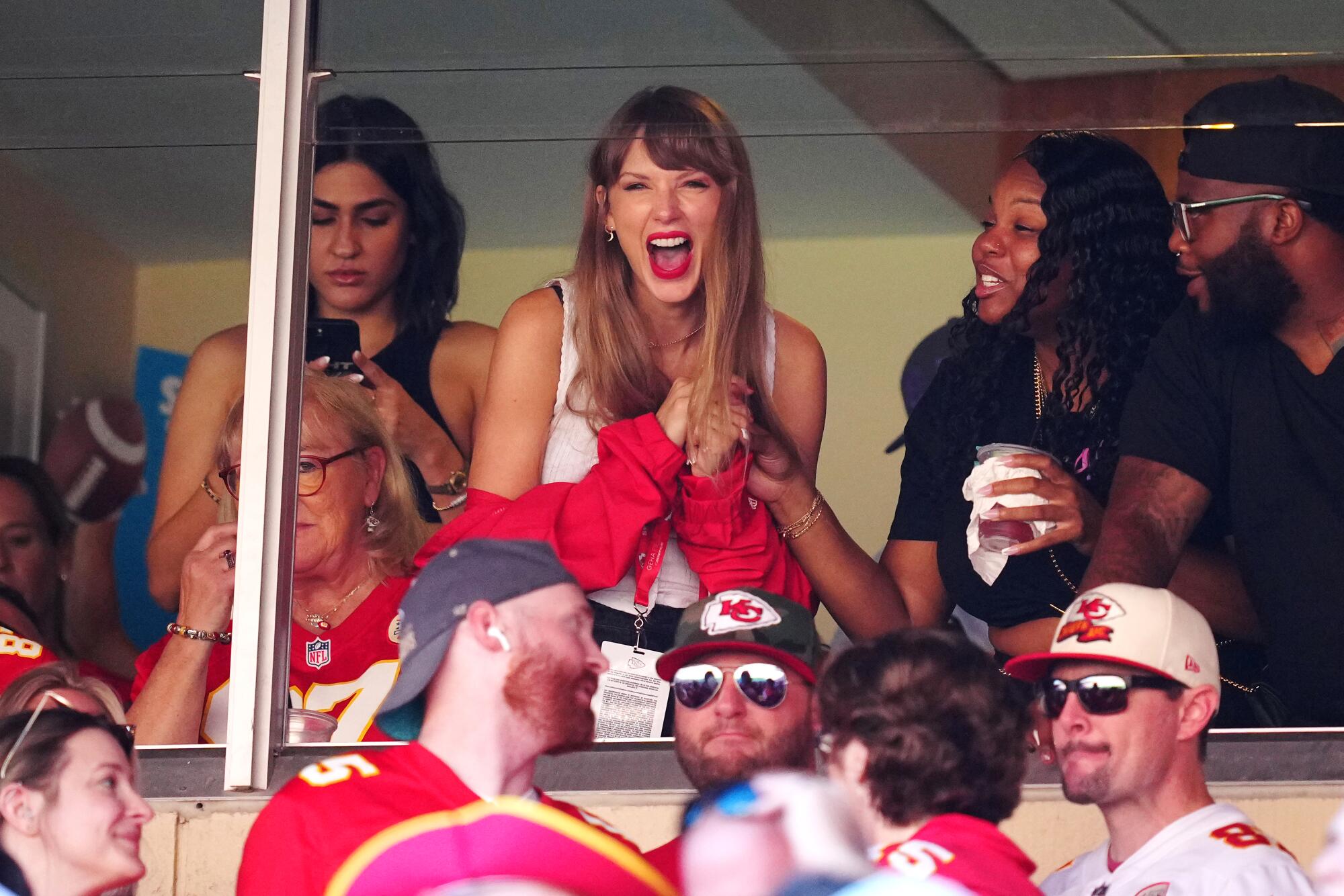 A woman cheers excitedly with other people around her