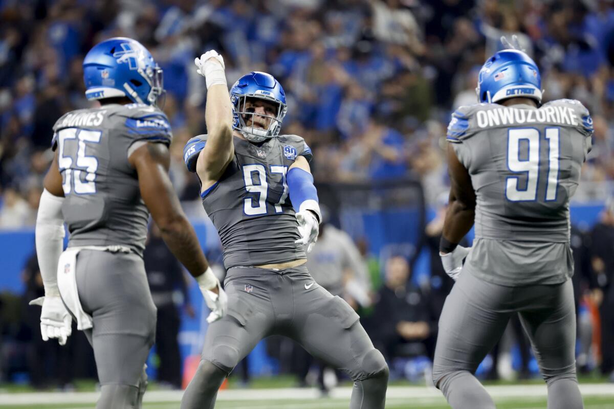 Lions Aidan Hutchinson (97), Derrick Barnes (55) and Levi Onwuzurike (91) celebrate against the Vikings.