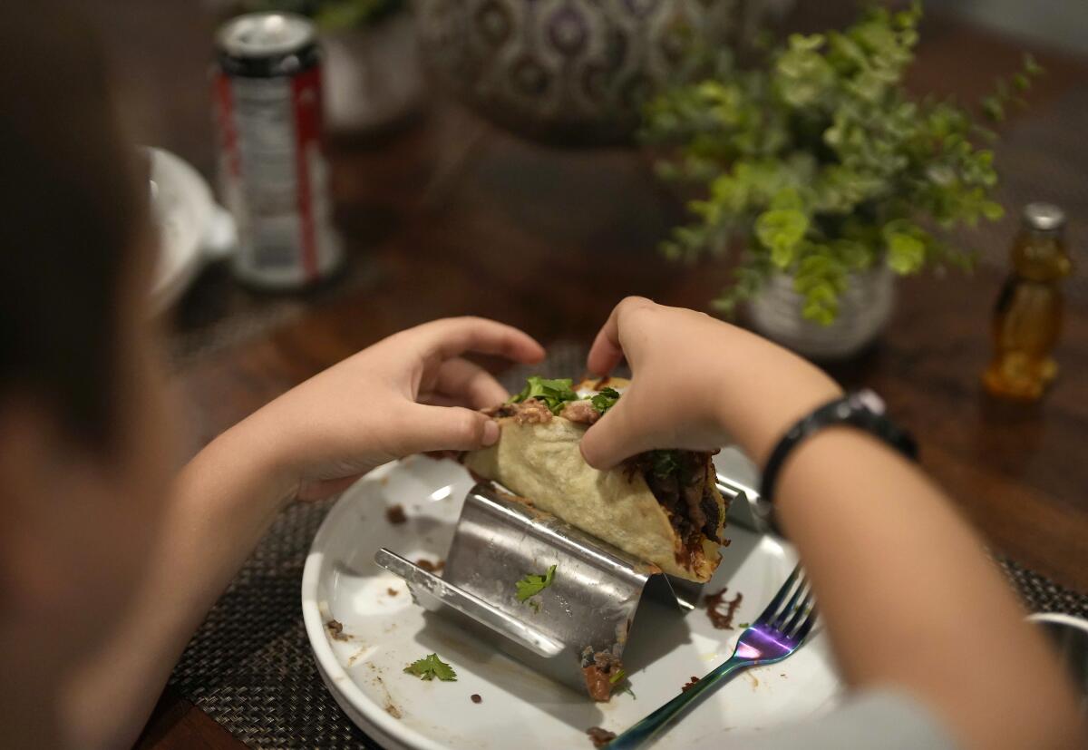 A boy prepares a taco 