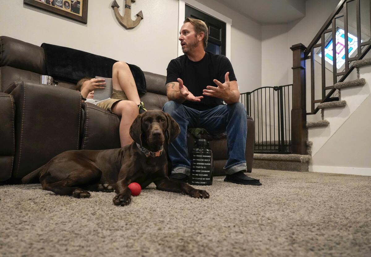 A father on a couch next to a child and a dog. 