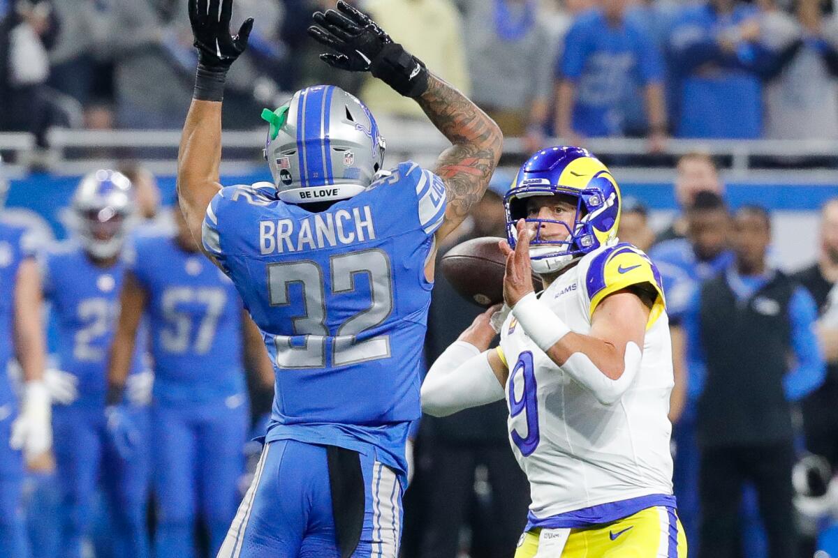 Rams quarterback Matthew Stafford (9) looks to pass around the Lions' Brian Branch.