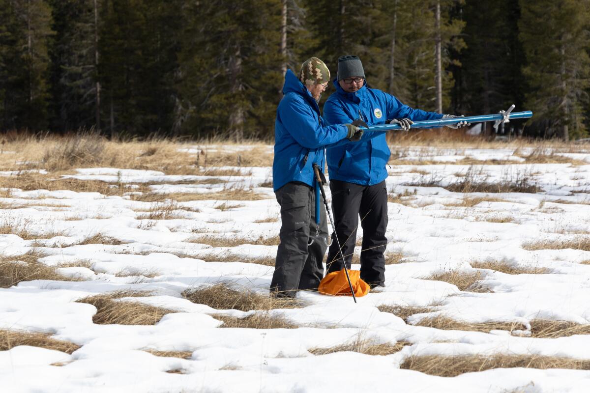 Researchers measure snowpack during the first media snow survey of the 2024 season at Phillips Station in the Sierra Nevada.