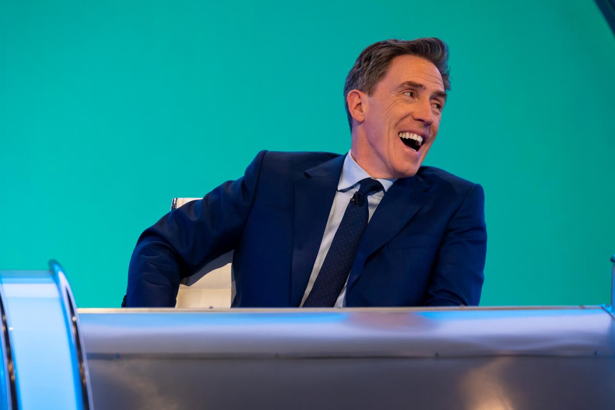 A man laughing on a game show set.