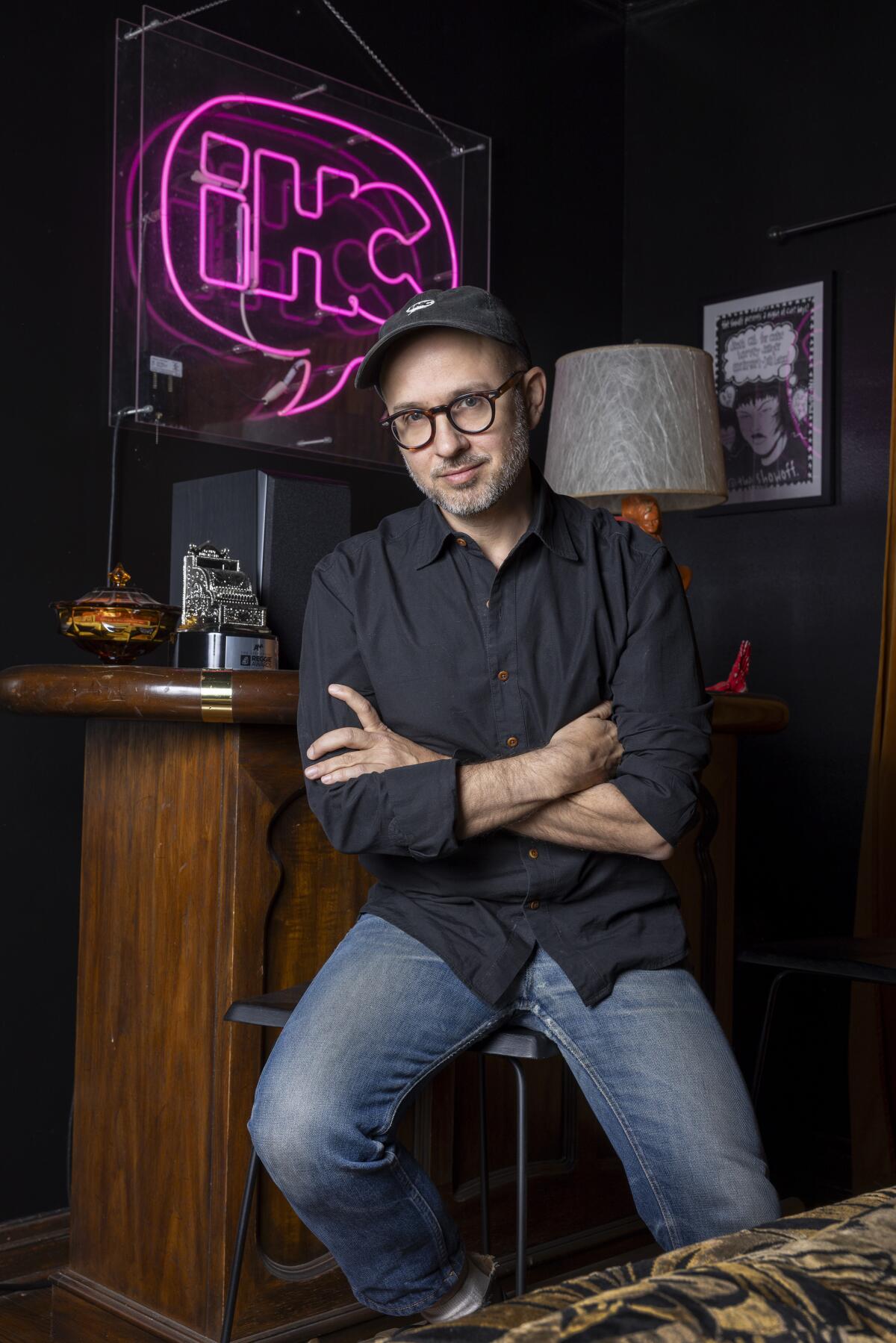 Man sitting on stool in hat and glasses