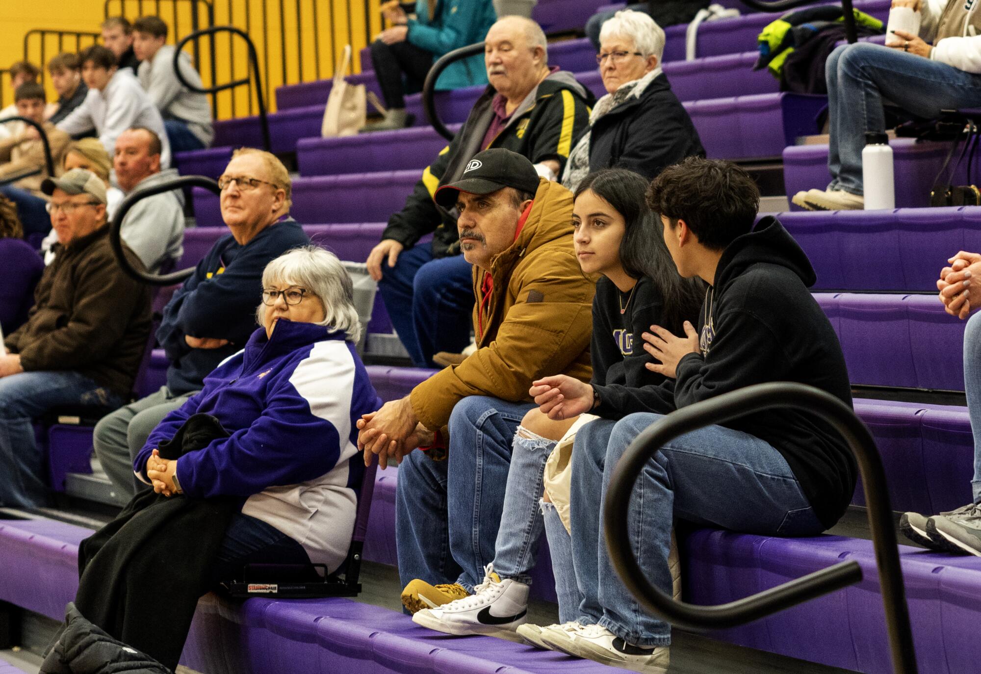 People sit in the stands watching a basketball game