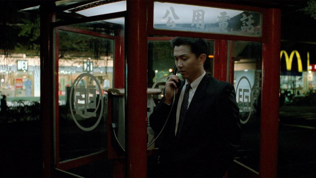 A man in a phone booth makes a call.