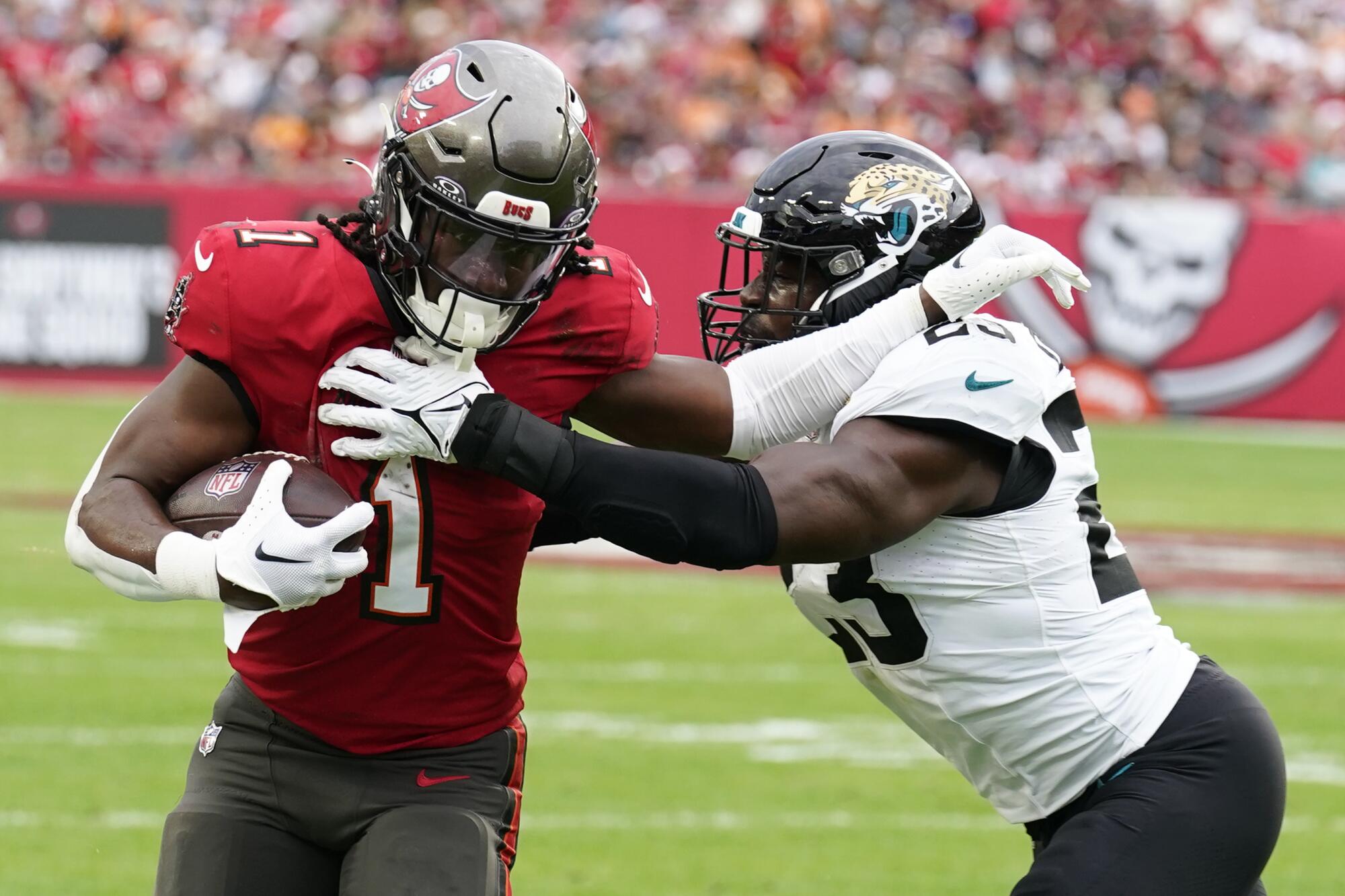 Tampa Bay Buccaneers running back Rachaad White tries to stiff arm Jacksonville Jaguars linebacker Foyesade Oluokun.