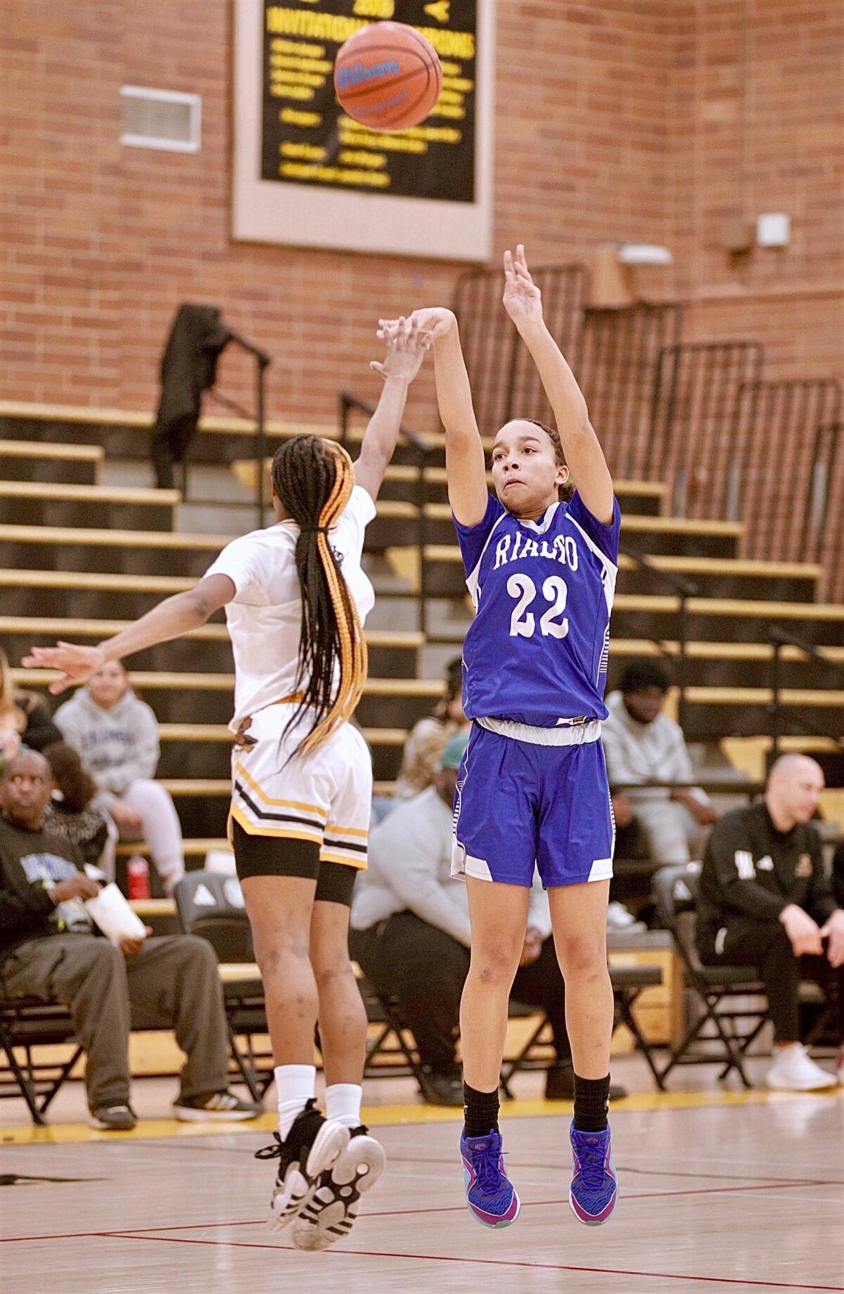 Rialto High's Carrington Davis shoots a three-pointer while closely defended by an opponent.