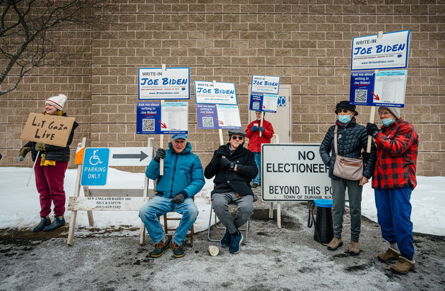 People sit outside of the Oyster River High school with signs to write Joe Biden into the Democratic ballot.