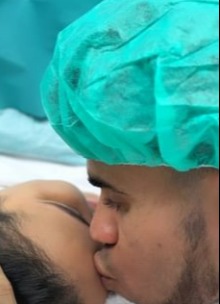 Luis kisses his wife's forehead during the birth