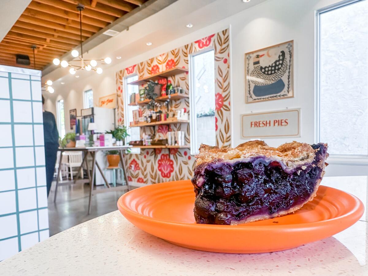 A slice of pie on an orange plate in a restaurant with a small retail area