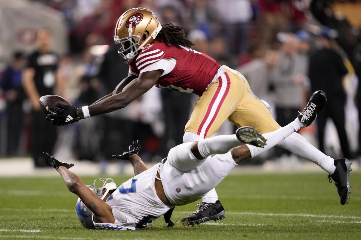 The 49ers' Brandon Aiyuk catches a 51-yard pass after it deflected off Lions cornerback Kindle Vildor (29).