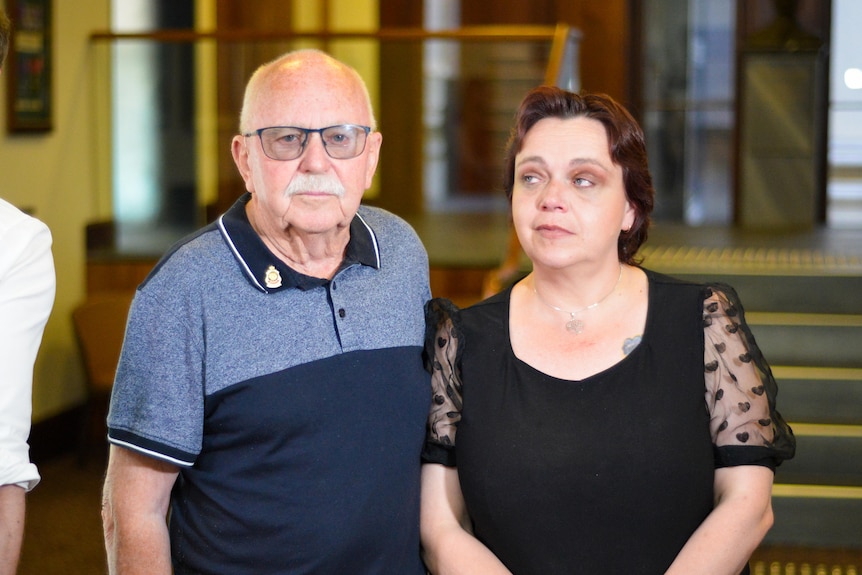 An elderly man standing next to a woman looking at him