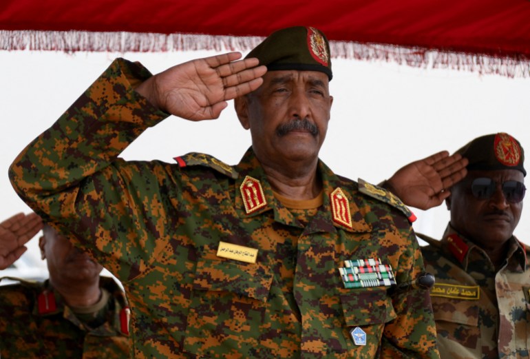 Sudan's General Abdel Fattah al-Burhan salutes as he listens to the national anthem after landing in the military airport of Port Sudan