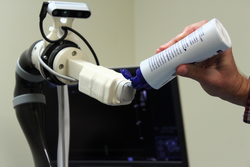 A health worker puts gel on the robot