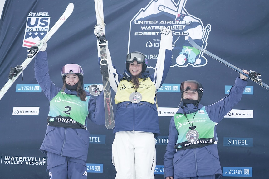 Three women stand on a podium