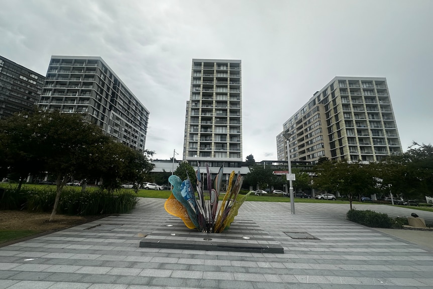 Three buildings visible with a colourful statue in front