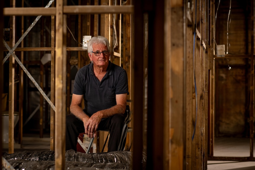 A man looks at the camera amongst a half constructed house