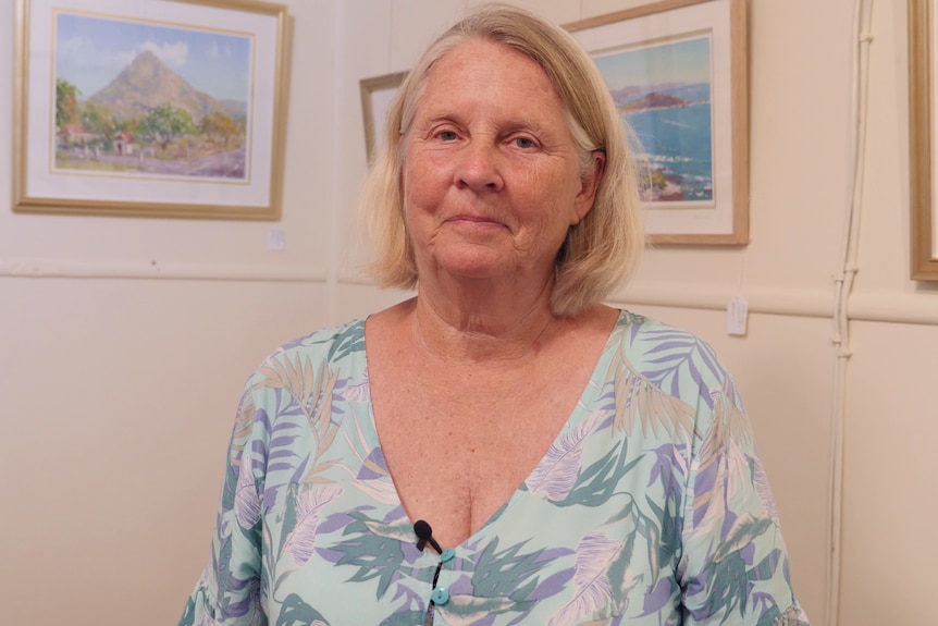 Woman stands and smiles at camera in art gallery.