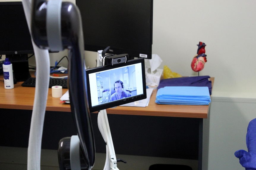 A doctor appears on a screen attached to a robot