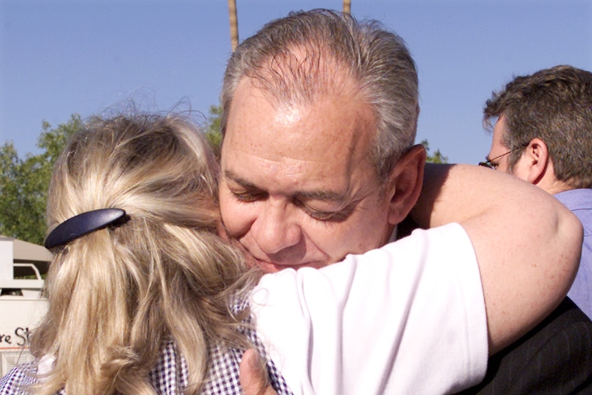 Chris Snodgrass embraces a female friend. They are outdoors.