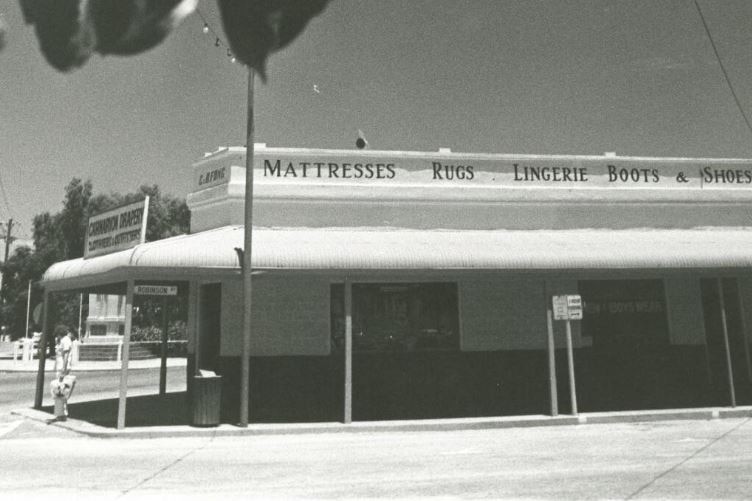 A black white photo of a shop on a corner