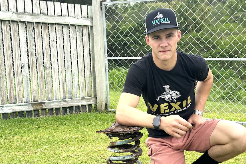 A young man wearing a black hat and black t shirt at home.