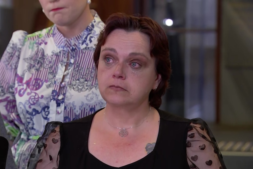 A woman in tears speaking at a press conference.