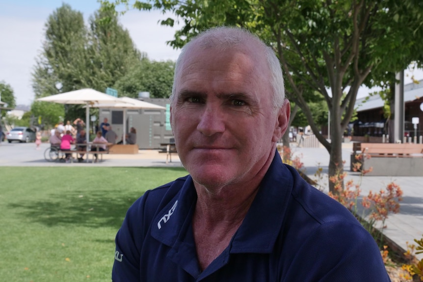 Man looks at camera wearing a dark polo shirt. 