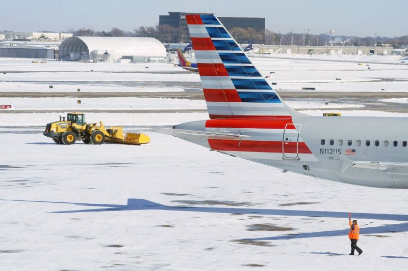 A snow sweeper attempts to pick up snow as an American Airlines plane is guided out at St. Louis -Lambert International Airport on Friday, February 4, 2022. More than 300 flights were canceled flying in and out of St. Louis in a 24-hour period, due to a snow storm beginning on February 3. Photo by Bill Greenblatt/UPI