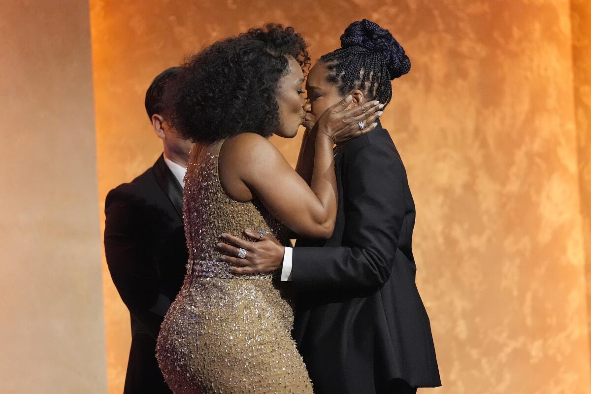 Two women kiss onstage at an awards ceremony