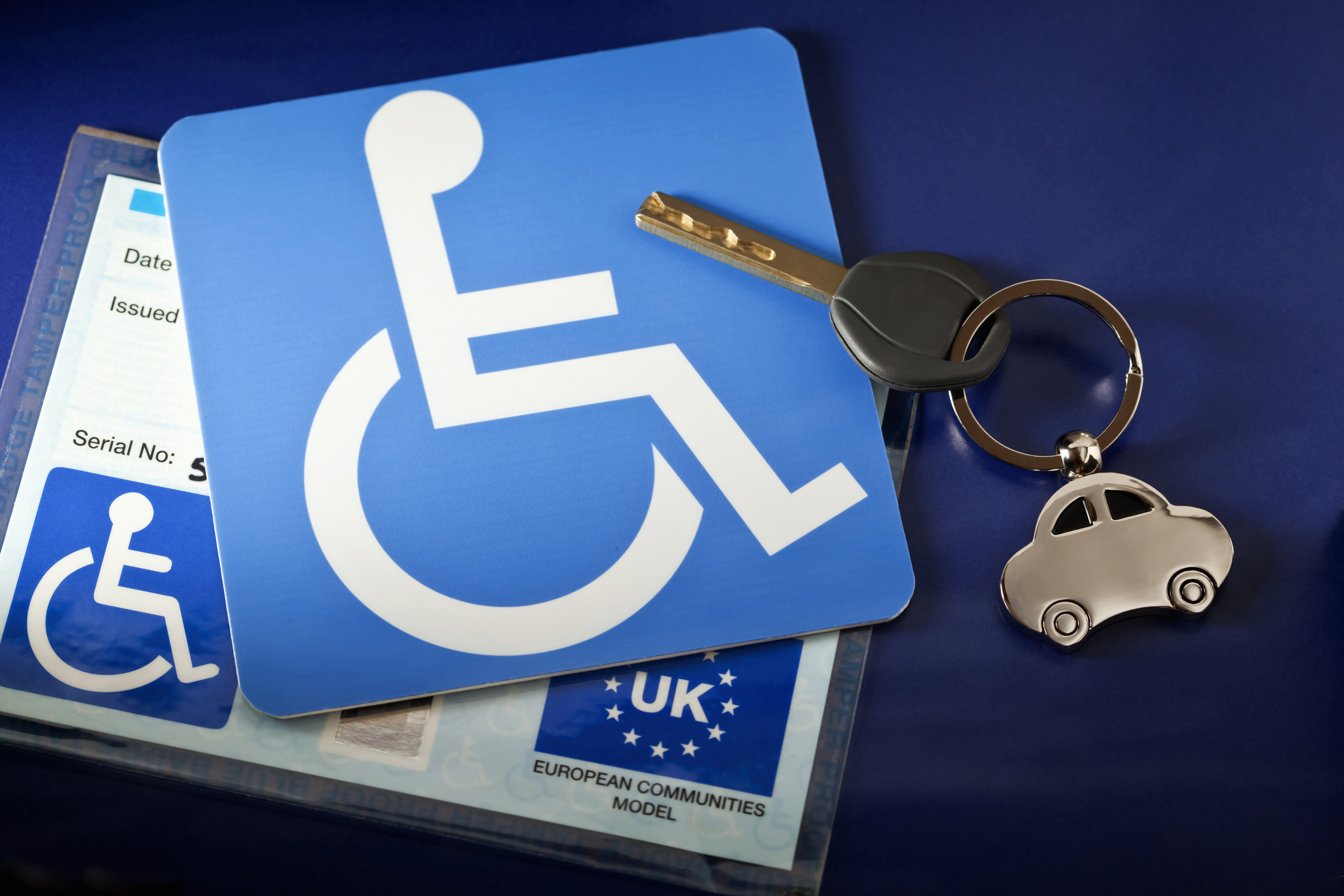 “The universal symbol for handicapped people, with a European Community handicapped persons parking permit for the UK, with a chrome car, key fob.”