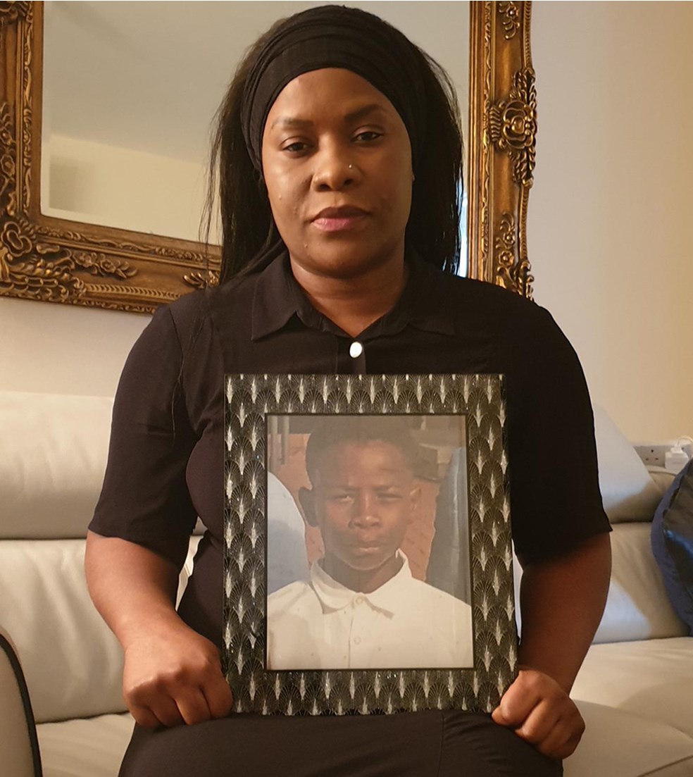 Christopher Kapessa's mother Alina Joseph holding a picture of him