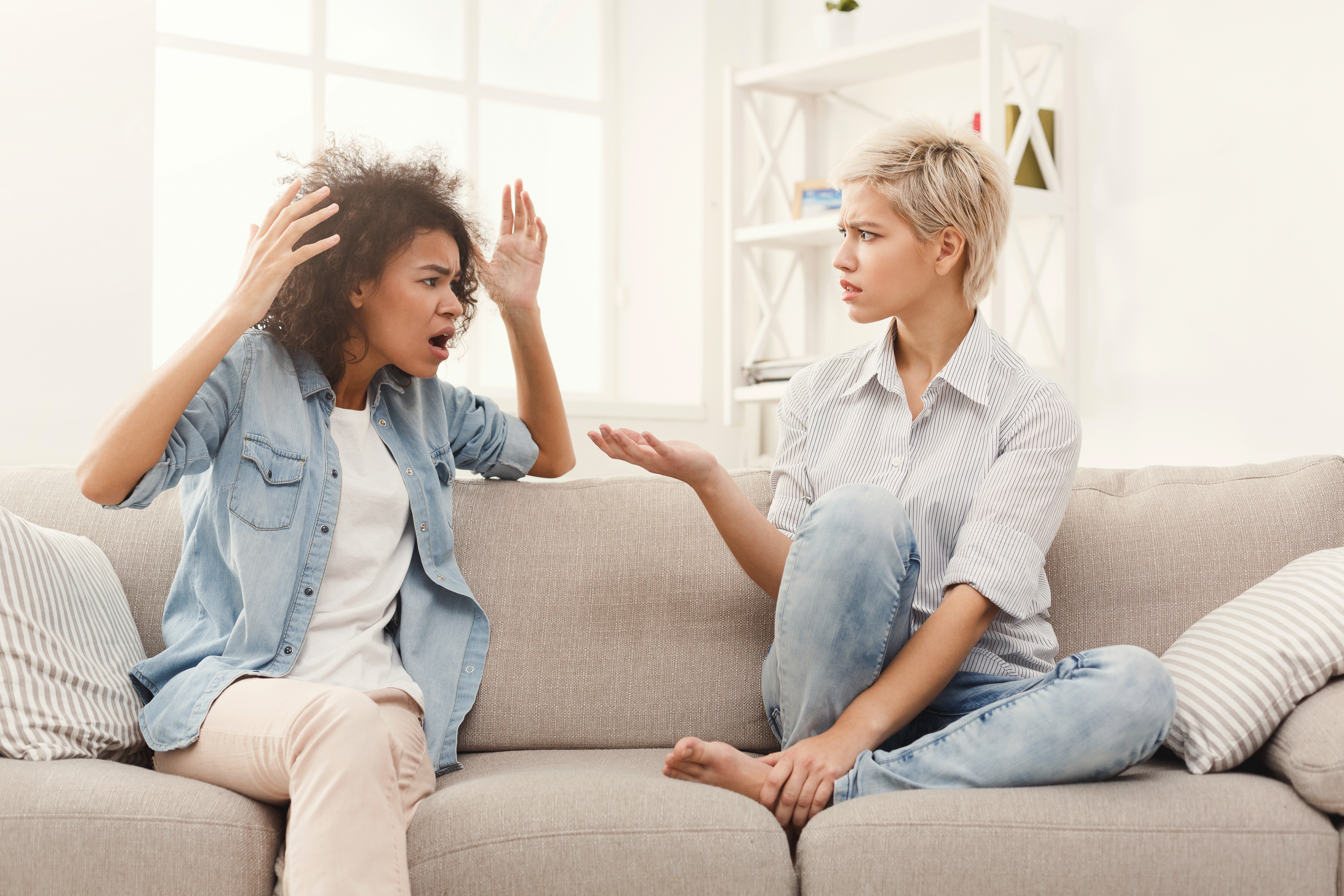 Two female friends sitting on sofa and arguing with each other. Friendship, quarrel, female disagreement, copy space